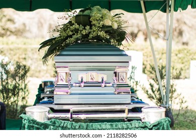 Green Coffin With Silver Handles With White Flowers At A Funeral Service