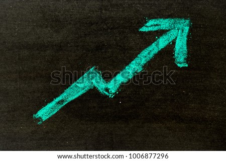 Green color hand drawing chalk in arrow upward shape on black board background (Concept of revenue increase, stock or business growth)