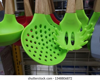 Green color plastic kitchen utensil with wooden handle