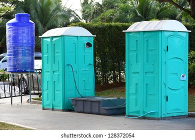 Green color Portable toilet with blue color water tank ready to service people for outdoor event