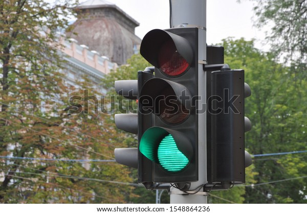Green color of a traffic light against the\
background of a modern city. Traffic\
Laws