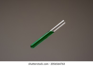 Green Colored Liquid In A Glass Test Tube. Close Up Studio Shot, Isolated On Gray Background, No People.