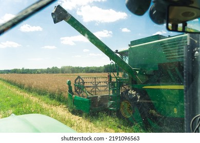 Green Combine Harvester Working In The Field. High Quality Photo