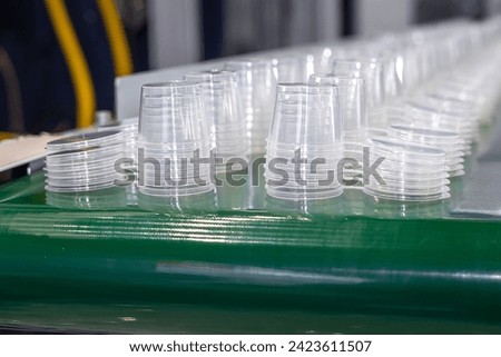 Green conveyor belt with rows of round plastic transparent food containers with lids. Production line for molding packaging made of transparent polypropylene PP