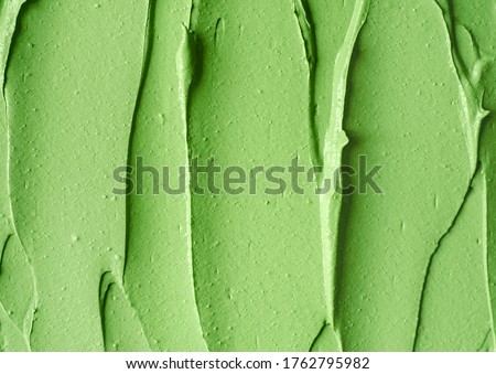 Green cosmetic clay (cucumber facial mask, avocado face cream, green tea matcha body wrap) texture close up, selective focus. Abstract background with brush strokes.