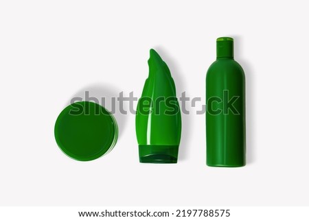 Green cosmetic jar and bottles on a light background.