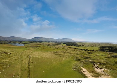 Green Country Side And Benbulben Flat Top Mountain In County Sligo, Ireland. Warm Sunny Day. Aerial View. Irish Landscape. Blue Cloudy Sky. Nature Scenery.