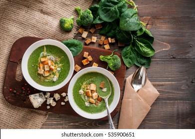 Green cream soup of spinach and broccoli. with the addition of parmesan and blue cheese with croutons. a wooden background. conception healthy food and diet.