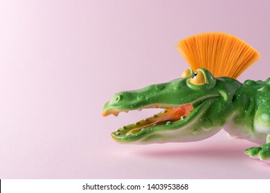 Green crocodile toy with mohawk on pastel pink background. Minimal art concept.
