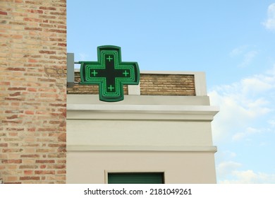 Green Cross Sign Of Drugstore On Building Wall Against Blue Sky