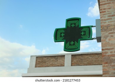 Green Cross Sign Of Drugstore On Building Wall Against Blue Sky