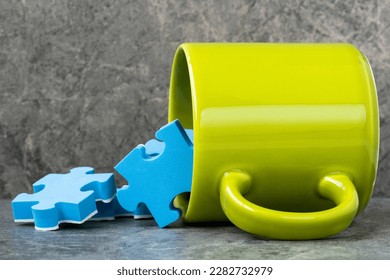 Green cup of coffee and scattered blue puzzle pieces. Creativity concept. - Powered by Shutterstock