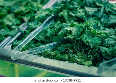 Green Curly Kale Chopped Tray With At Salad Bar With Plastic Tongs In High-end Grocery Store Near Dallas, Texas, America. Colorful Fresh And Organic Vegetable In Self-service Counter.