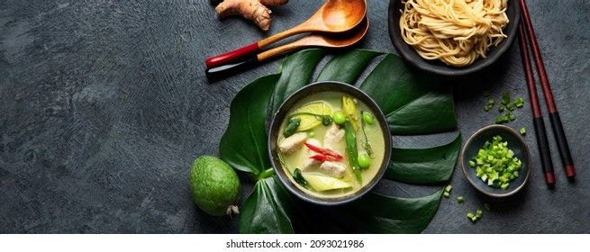 Green curry with chicken in bowl on dark background. Traditional Asian food. Top view, flat lay, copy space, panorama