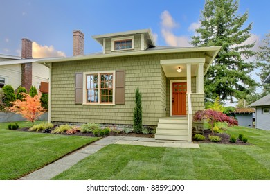 Green cute small craftsman house with orange door