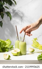 Green detox smoothies in two bottles standing on a white table, front view composition, healthy lifestyle concept