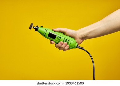 Green Die Grinder In Hands Isolated On Yellow Background