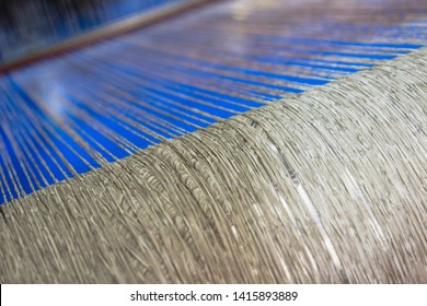 Green Dirty Dark Brown Cotton Wool Threads In A Factory Industrial For Production Of Clothes Materials Yarn Individual Threads Coming Together On A Drum Tube Pipe Bright Blue Background Floor 