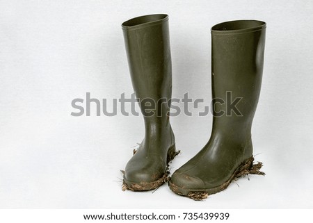Green dirty rubber boots against white background.