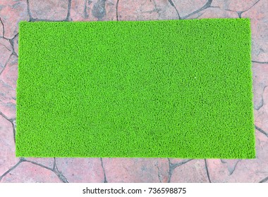 Green door mat on cement floor