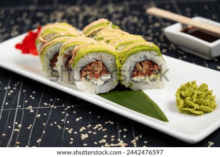 Green dragon sushi roll with eel, avocado, cucumber and ginger, accompanied with fried tempura shrimp. Traditional asian rice sushi healthy seafood