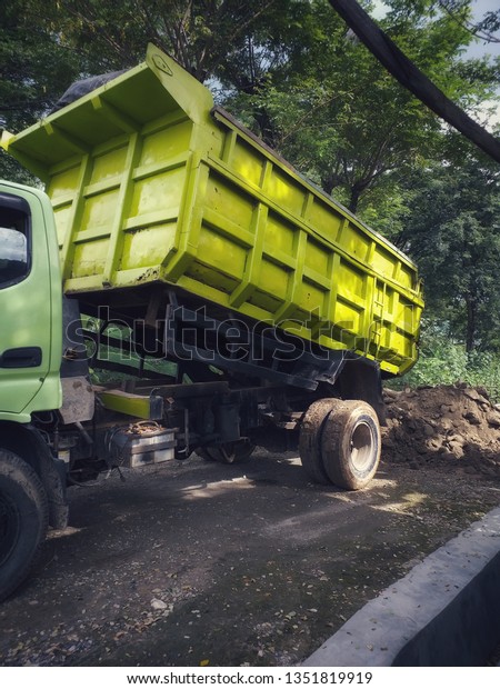 Green Dump truck is\
moving down sand 