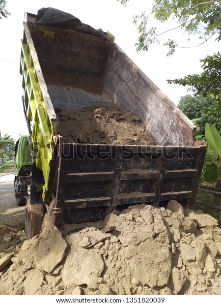 Green Dump truck is\
moving down sand 