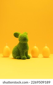 Green Easter Bunny, rabbit with three yellow candles of eggs shape on matching monochrome orange background. Minimal Happy Easter holiday concept. Creative Easter greeting card, copy space, vertical - Shutterstock ID 2269509189