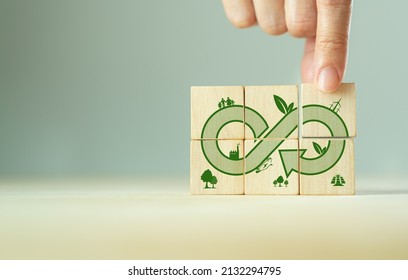 Green eco infinity, net zero, circular economy, renewable enwergy and save the world concept. Sustainable development.  Hand puts wooden cubes with green econ infinity on grey background. Eco banner.