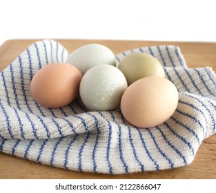 Green Eggs And Brown Chicken Eggs On Blue And White Striped Dishcloth On Bread Board, Concept, Homey, Cabin, Urban Farming Shallow Depth Of Field Point Of View Shot