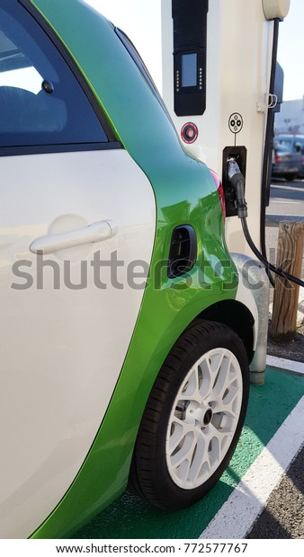 a\
green electric car charging loading by cable in park\
