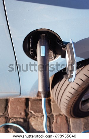 Green electric car at charging station with power outlet