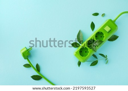 Green electric power socket with fresh leaves top view. Renewable and saving energy, eco or green power consumption concept.