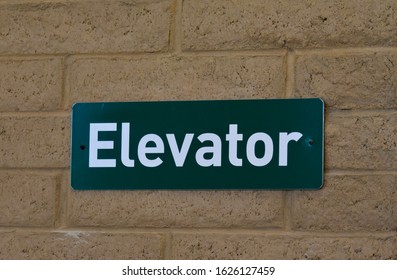 Green Elevator Sign On Brick Wall