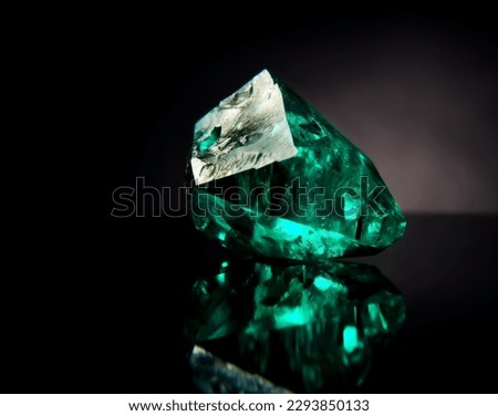 Green Emerald gemstone with rough cut or uncut. Dark studio background. 
