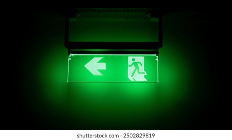 Green emergency exit sign in a dark room - Powered by Shutterstock