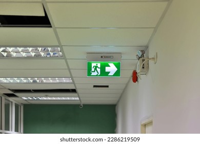 Green emergency exit sign showing the way to escape. Fire exit in the building.