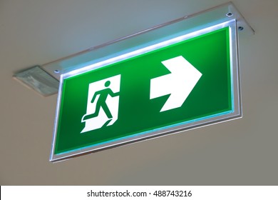 green emergency exit sign showing the way to escape