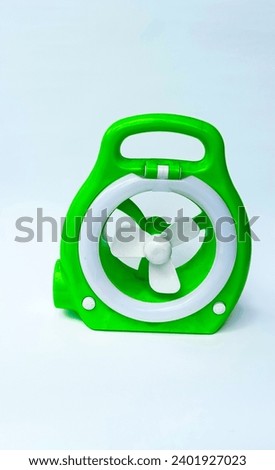 Green emergency fan and lamp with power source via battery that can be recharged or used by a power bank with white background.