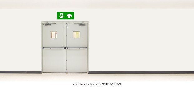 Green emergency fire exit sign or fire escape on ceiling for doorway or door exit in the building for evacuation in the event of a fire and safety prevent or prevention and rescue.