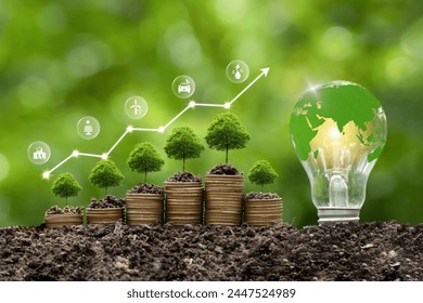 Green energy, eco energy concept. Trees growing on coin stacks symbolize green investments. A graph with renewable energy icons shows growth, an Earth-filled light bulb highlights the global impact. - Powered by Shutterstock