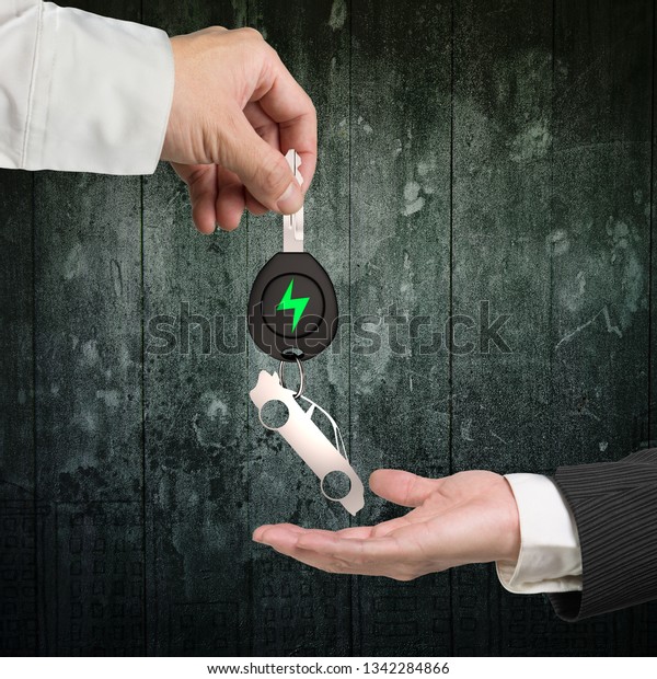 Green
energy electric car and lightweight high strength speed concept.
One hand giving electric car key with sheet metal keyring in sports
car shape to another, on dirty wall
background.