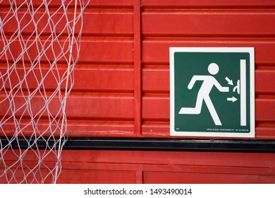 Green Escape Exit Sign Over Red Metal Door.