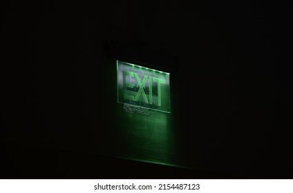 Green EXIT Sign Against Dark Background Inside A Hospital Building.