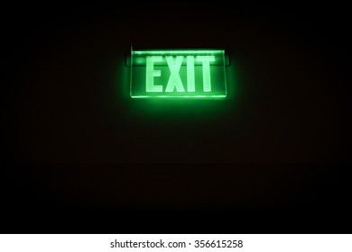 Green Exit Sign Isolated In Dark Black Room

