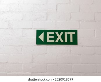 Green exit sign on white brick wall - Powered by Shutterstock