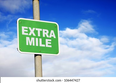 Green extra mile sign against a blue sky
