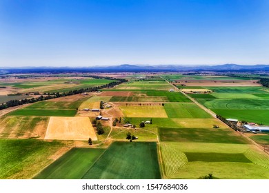 Green Farm Fields With Irrigation And Cultivation On Shores Of Hunter River In Hunter Valley Region Of Australia Around Farm House Under Blue Sky On A Sunny Day - Aerial View.