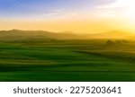 green field in countryside at sunset in the evening light. beautiful spring landscape in the mountains. grassy field and hills. rural scenery