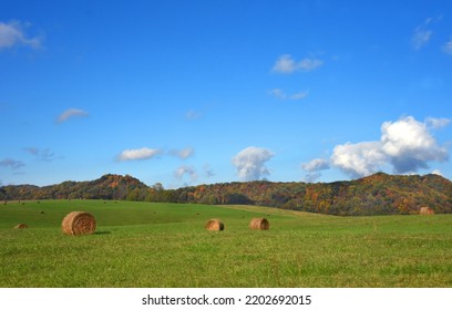 Green Field Has Round Hay Bales.  Appalachian Mountains Fill Back Of Photo, With Fall Colors Dotting Mountain.